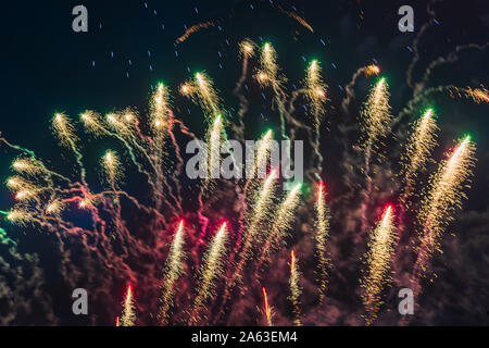 Preiswertes Feuerwerk über der Stadt Rot, Grün und Gelb auf den blauen Himmel. Hell und glänzend. Für jeden Zweck. Feier Konzept. Stockfoto