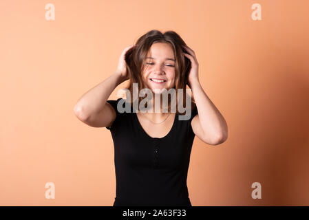 Das Mädchen glättet Ihr Haar, auf einem hellen orange hinterlegt. Stockfoto