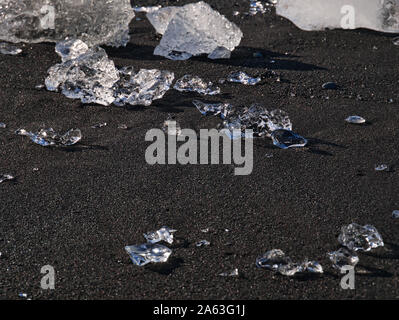 Kleine Eisbrocken Funkeln auf dem schwarzen Sand an der Diamond Beach Stockfoto