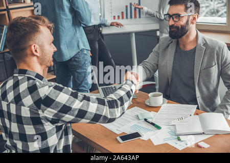 Startupers zusammen arbeiten im Büro Männer sitzen die Hände schütteln viel Lächeln glücklich Stockfoto
