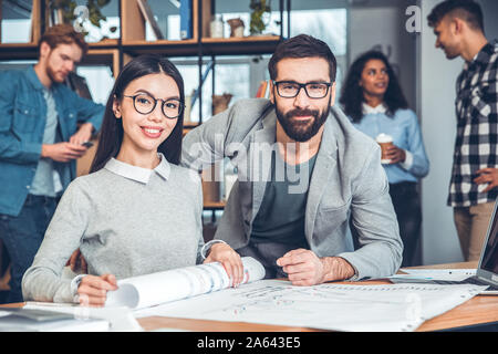 Startupers zusammen arbeiten im Büro Frau in Brillen sitzen mit Kollegen suchen Kamera heiter Stockfoto