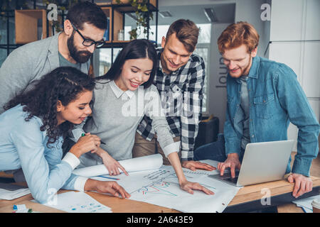 Startupers zusammen arbeiten im Büro in der Nähe von Tabelle in Diagramm freudige suchen Stockfoto