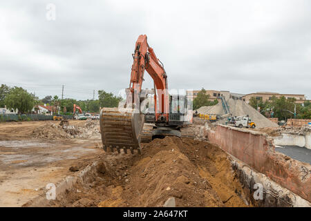 Hitachi-Hydraulikbagger gräbt während Erdungsarbeiten auf einer aktiven Baustelle durch den Boden. Stockfoto