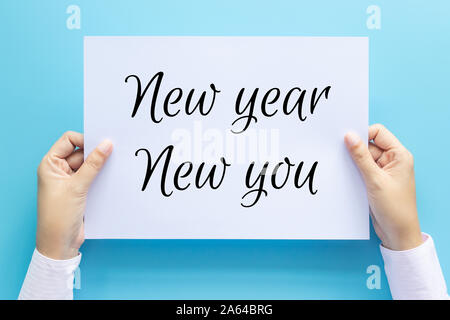Hand mit weißem Papier mit Text Neues Jahr, neue Sie isoliert auf blauen Hintergrund. das unternehmerische Ziel, Ziel, Motivation und Inspiration Konzepte Stockfoto