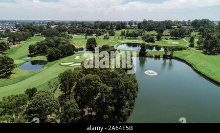 Antenne drone View Golf Course Fahrrinne, Wasserhindernisse, Brunnen, Grün mit Bunkern umgeben von Bäumen Stockfoto