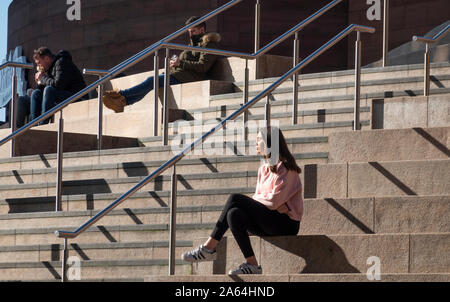 Schöne junge Frau, die die Sonne auf die Schritte der Liverpool One Shopping Center Stockfoto