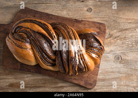 Schokolade Swirl Brot oder Brioche Brot. Hausgemachten süßen Wüste Gebäck - Schokolade swirl Brot (babka) auf Holz- Hintergrund, Ansicht von oben, kopieren. Stockfoto