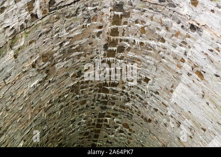 Kalkablagerungen in einem alten Steinhaus, Tunnel, mit Stalaktiten gebildet Stockfoto