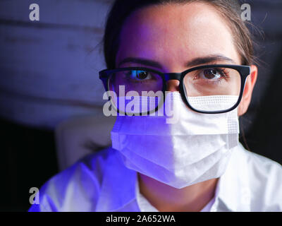 Nahaufnahme von einer Krankenschwester. Arzt, Krankenschwester, hinter der Maske eines Chirurgen. Closeup Portrait einer jungen kaukasischen Frau Modell mit schwarzen Gläsern Stockfoto