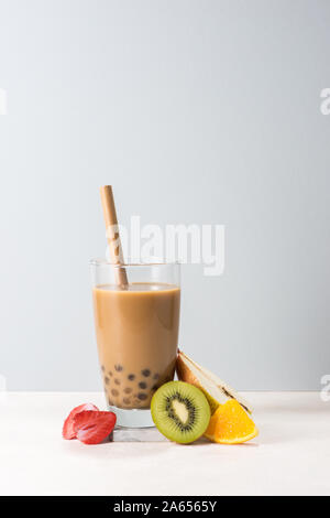 Boba / buble Kaffee Glas mit Kiwi, Erdbeere, Orange Scheiben auf blauem Hintergrund. Stockfoto