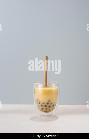 Bubble boba Tee mit Milch und Tapioka Perlen im Glas auf blauem Hintergrund Stockfoto