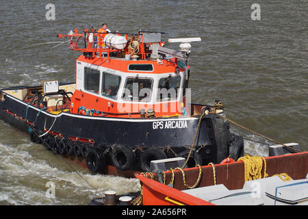 Eine orange und schwarz Tug Boat auf der Themse durch Drücken einer kommerziellen Barge bis Fluss an Geschwindigkeit mit Seilen und Utensilien an Bord Stockfoto