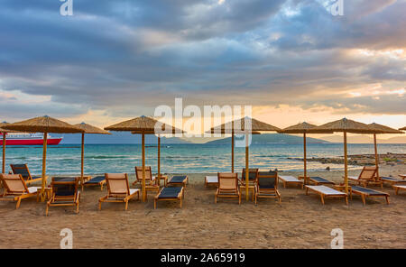 Panorana leerer Strand mit Liegestühlen und Sonnenschirmen am Meer und bunten Wolken bei Sonnenuntergang, Aegina Island, Griechenland - griechische Landschaft - seasc Stockfoto