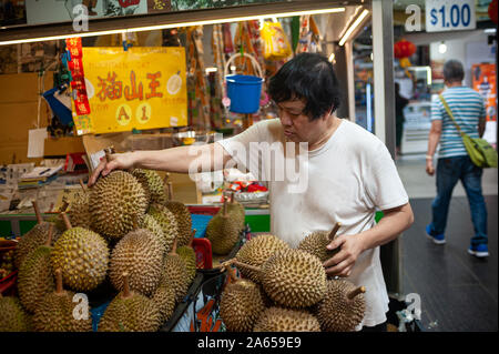 10.02.2019, Singapur, Republik Singapur, Asien - ein Mann wiegt und türmt sich frische durians an einem Marktstand in der Chinatown. Stockfoto