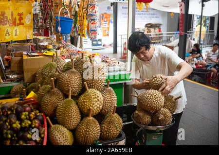10.02.2019, Singapur, Republik Singapur, Asien - ein Mann wiegt und türmt sich frische durians an einem Marktstand in der Chinatown. Stockfoto
