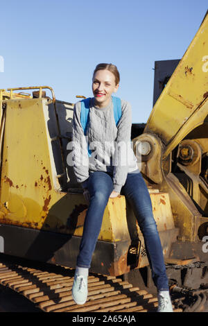 Junge Frau sitzt auf einem gelben Bagger. Stockfoto