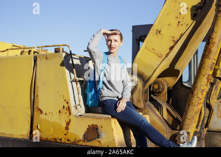 Junge Frau sitzt auf einem gelben Bagger. Stockfoto