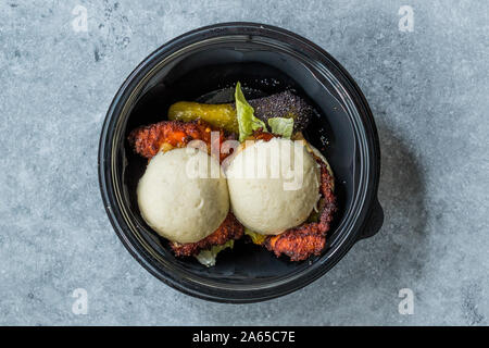 Nehmen Gua Bao Burger mit knusprigen Hähnchen und Red Hot Chili und Soße, Brötchen Relish in Kunststoff Platte Box Container/Paket. Fast Food. Stockfoto