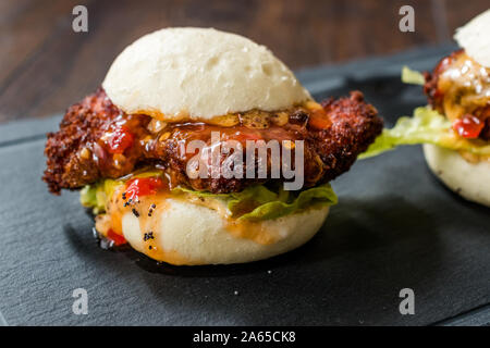 Gua Bao Burger mit knusprigen Hähnchen und Red Hot Chilli Relish Sauce Brötchen. Fast Food. Stockfoto