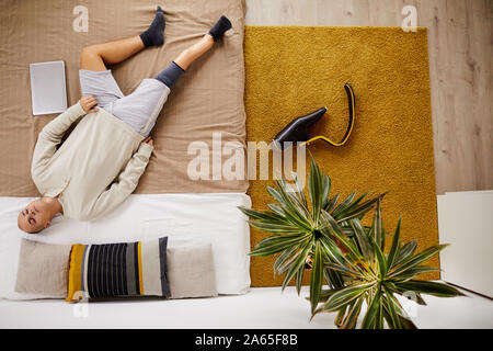 Hohe Betrachtungswinkel von jungen behinderten Mann auf dem Bett liegen und schlafen im Wohnzimmer Stockfoto
