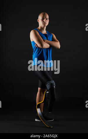 Portrait von paralympischen Läufer in Sport Kleidung Stehen mit verschränkten Armen an der Kamera auf schwarzem Hintergrund Stockfoto