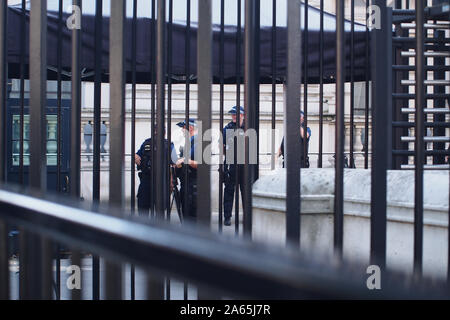 Vier bewaffnete Polizisten bewachen den Eingang von Downing Street, Westminster, London, hinter heavy duty, groß, Bügeleisen Fechten. Stockfoto