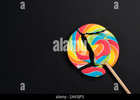 Swirl Runde abgebrochen Lollipop auf schwarzem Hintergrund. Konzept der ungesunde Nahrungsmittel, Süßwaren und Süßigkeiten Tag Stockfoto