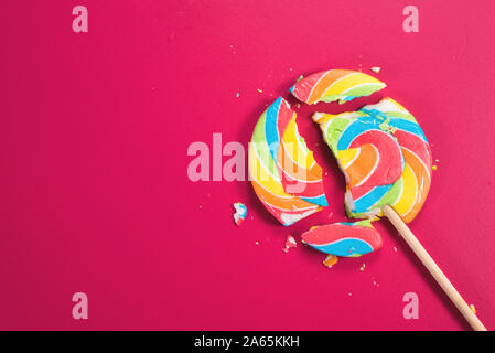 Swirl Runde abgebrochen Lollipop auf rosa Hintergrund. Konzept der ungesunde Nahrungsmittel, Süßwaren und Süßigkeiten Tag Stockfoto