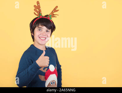 Lustig Kind in einem Rudolph Rentier Weihnachten Kostüm auf gelbem Hintergrund Stockfoto
