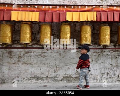 LHASA, Tibet autonomen Region, China - ca. Oktober 2019: Eine kleine Tibetische Junge vor gebetsmühlen. Stockfoto