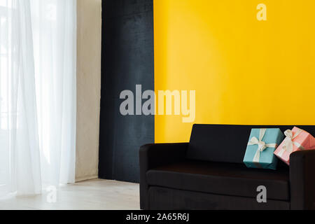 Schwarzes Sofa mit einem Geschenk in die Innenausstattung des Zimmers mit einem gelben Hintergrund Stockfoto