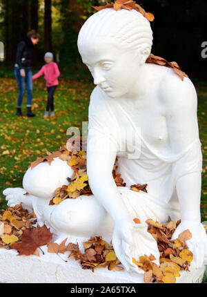 22 Oktober 2020, Sachsen-Anhalt Wörlitz: Besucher der Wörlitzer Park hinter der Skulptur des shellfinder, die am Ufer des Sees unter vielen Bäumen steht und ist mit Herbstlaub bedeckt. Der Park gehört der Dessau-Wörlitzer Gartenreich, die von Fürst Leopold III. Friedrich Franz von Anhalt-Dessau von 1764 erstellt wurde (1740-1817) als ersten Landschaftspark im englischen Stil auf dem Festland. Im November 2000 die umfangreiche Dessau-Wörlitzer Gartenreich, dessen Kern ist der Wörlitzer Park, wurde von der Unesco als Weltkulturerbe anerkannt. Foto: Waltraud Grubitzsch/dpa-Zentral Stockfoto