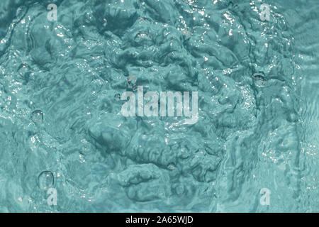 Schwimmbad Hintergründe. Türkis Hintergrund Textur des Blubbernden und wellige Muster von Wasser in einem Pool mit Sonnenterrasse Reflexionen. Makro. Stockfoto