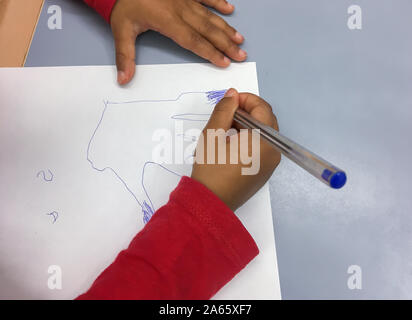 Kinder zieht mit einem blauen Stift auf ein weißes Blatt Stockfoto