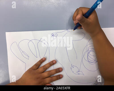 Kinder zieht mit einem blauen Stift auf ein weißes Blatt Stockfoto