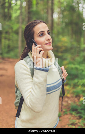 Frau mit smart phone bei einem Spaziergang durch den Wald. Stockfoto