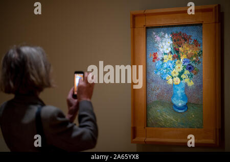 Potsdam, Deutschland. 24 Okt, 2019. Eine Frau fotografiert nach einer Pressekonferenz vor der Eröffnung der Ausstellung "Van Gogh. Immer noch leben", die in das Museum Barberini: das Bild "Blumen in blauer Vase'. Die Ausstellung zeigt 27 Stillleben des Künstlers und kann ab 26. Oktober 2019 bis 2. Februar 2020 gesehen werden. Credit: Monika Skolimowska/dpa-Zentralbild/dpa/Alamy leben Nachrichten Stockfoto