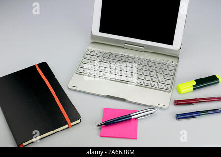 Tablet-PC mit Tastatur, fluoreszierenden Marker, rote und blaue Markierungen, Stift, Haftnotizen und Notizblock auf weißem Hintergrund Stockfoto