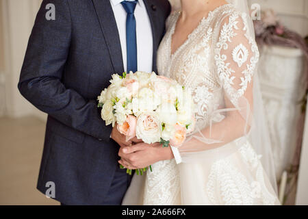 Hochzeit Strauß Blumen in der Hand der Braut und Bräutigam Braut in einem Brautkleid und Bräutigam in einem Anzug mit einem Blumenstrauß Stockfoto