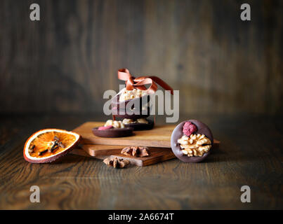 Mix Nüsse, trockene Früchte und Schokolade Bonbons Ringe auf einem dunklen Hintergrund. Landhausstil. Leckere Sweeties. Stockfoto