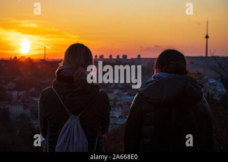 Zwei Freunde, mit Blick auf den Sonnenuntergang über Vilnius, Panorama mit Gebäuden und der Fernsehturm Stockfoto