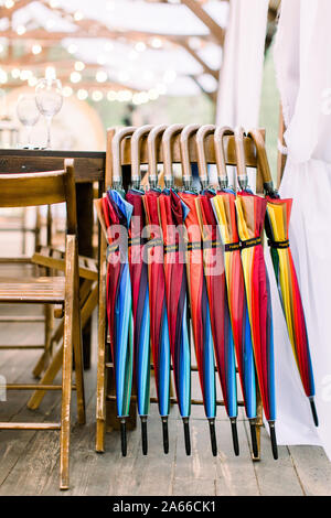 Der bunte Sonnenschirme auf dem hölzernen Stuhl für Gäste der Hochzeit im Freien. Hochzeit oder Abendessen feier Veranstaltung ourdoors Stockfoto