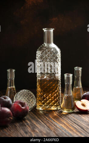 Schnaps oder Rakija traditionellen Balkan Obst Schnaps. Pflaumenschnaps slivovica in ein Glas, das cokanj und Flasche auf einem Holztisch aufgerufen wird Stockfoto