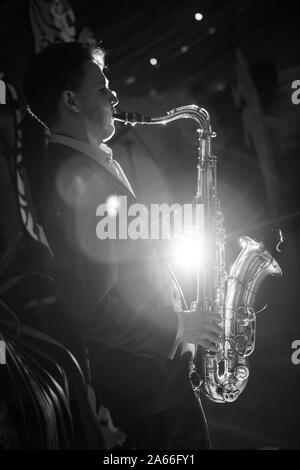 Jungen kaukasischen Mann spielt Saxophon in Schwarz und Weiß Stockfoto