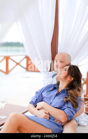 Glückliches Paar sitzt auf Resort, das Trinken von Wein in der Nähe von Kerzen. Stockfoto