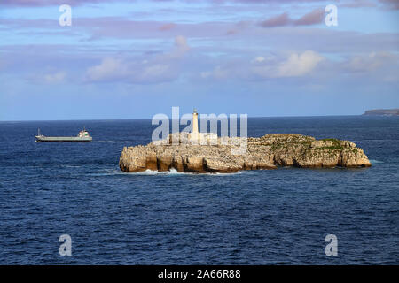 Frachtschiff Verlassen der Santander Hafen mit dem Leuchtturm in der Mouro Insel, Santander (Spanien) Stockfoto