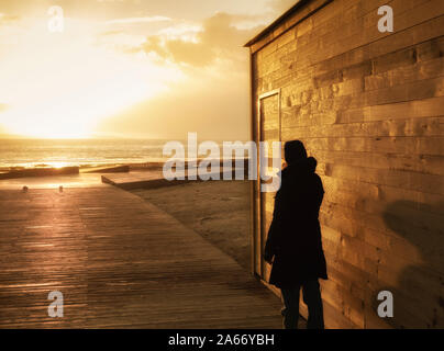 Ansicht der Rückseite Frau am Strand Promenade bei Sonnenuntergang Stockfoto