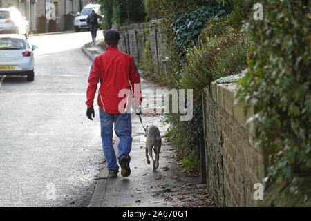 Ein Mann, der seinen Hund auf der Bridge Street, New Mills, Derbyshire Stockfoto