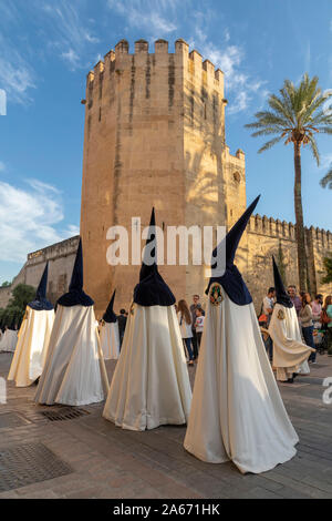 Büßer in konischer Hüte vorbei an den Royal Botanical Gardens während der Semana Santa (Karwoche), Cordoba, Andalusien, Spanien Stockfoto