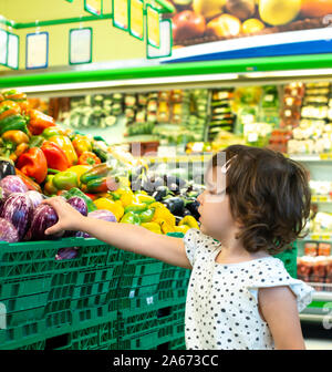 Kind shopping Auberginen im Supermarkt. Konzept für den Kauf von Obst und Gemüse im Supermarkt. Kleines Mädchen halten Sie den Warenkorb. Stockfoto